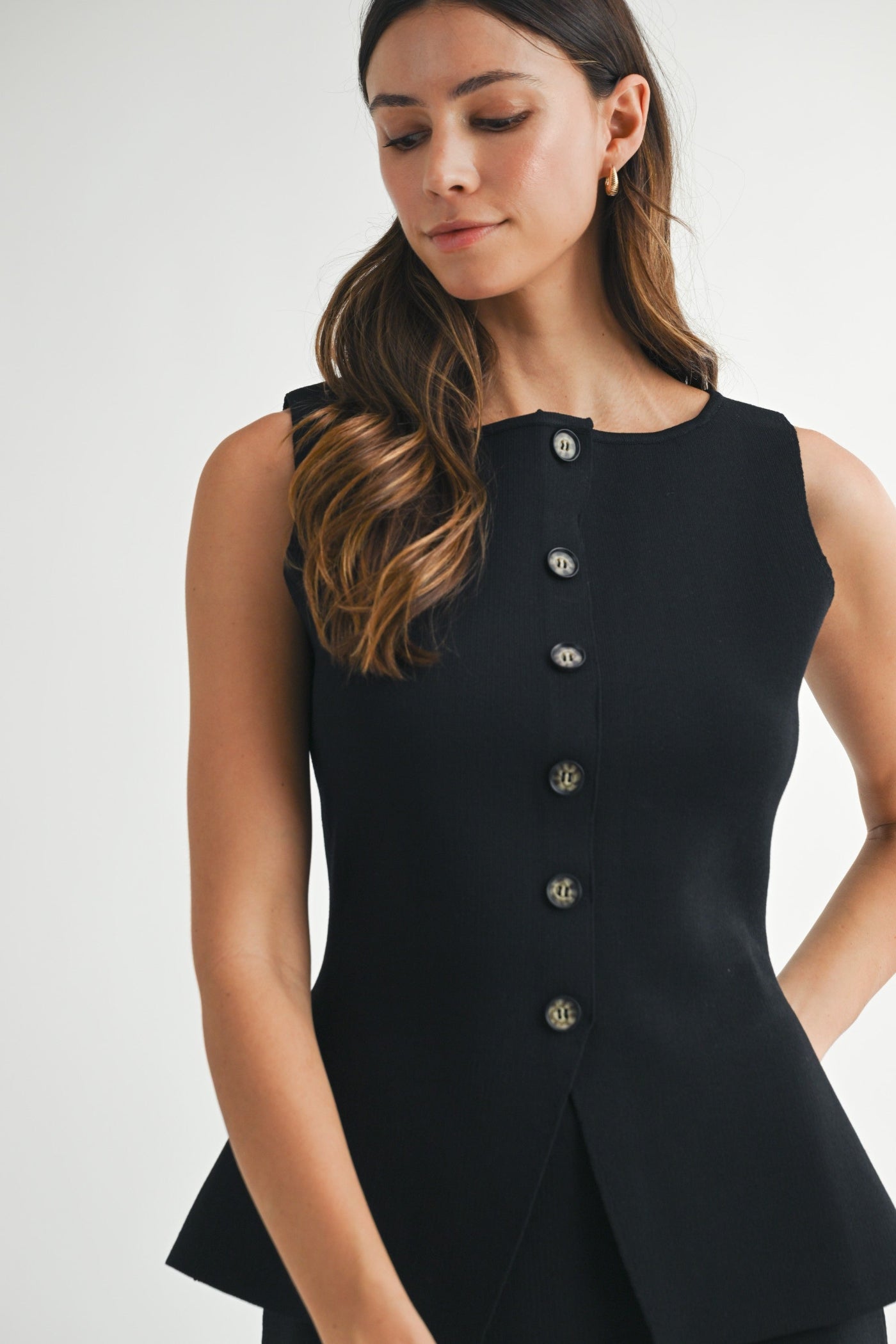 MABLE BLACK KNIT SLEEVELESS BUTTON TOP – A STRUCTURED KNIT VEST WITH PEPLUM FLARE DETAIL