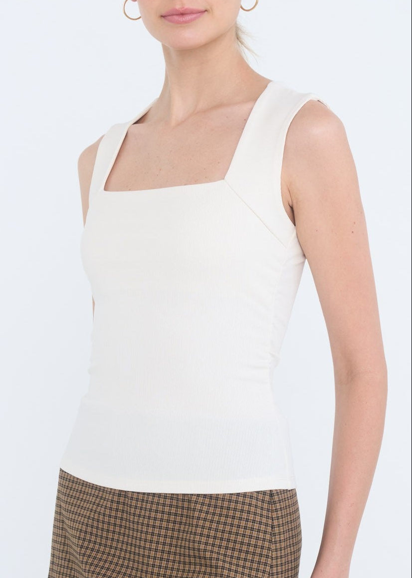 Woman wearing a white sleeveless top and brown checkered skirt on a white background